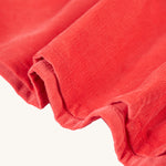 The red corduroy material texture up close from the Frugi Amilie Party Dress - True Red/Robin