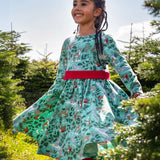 A child standing in the middle of a forest and wearing the the Frugi party skater dress in festive forest available at Babipur showing the gather of the dress