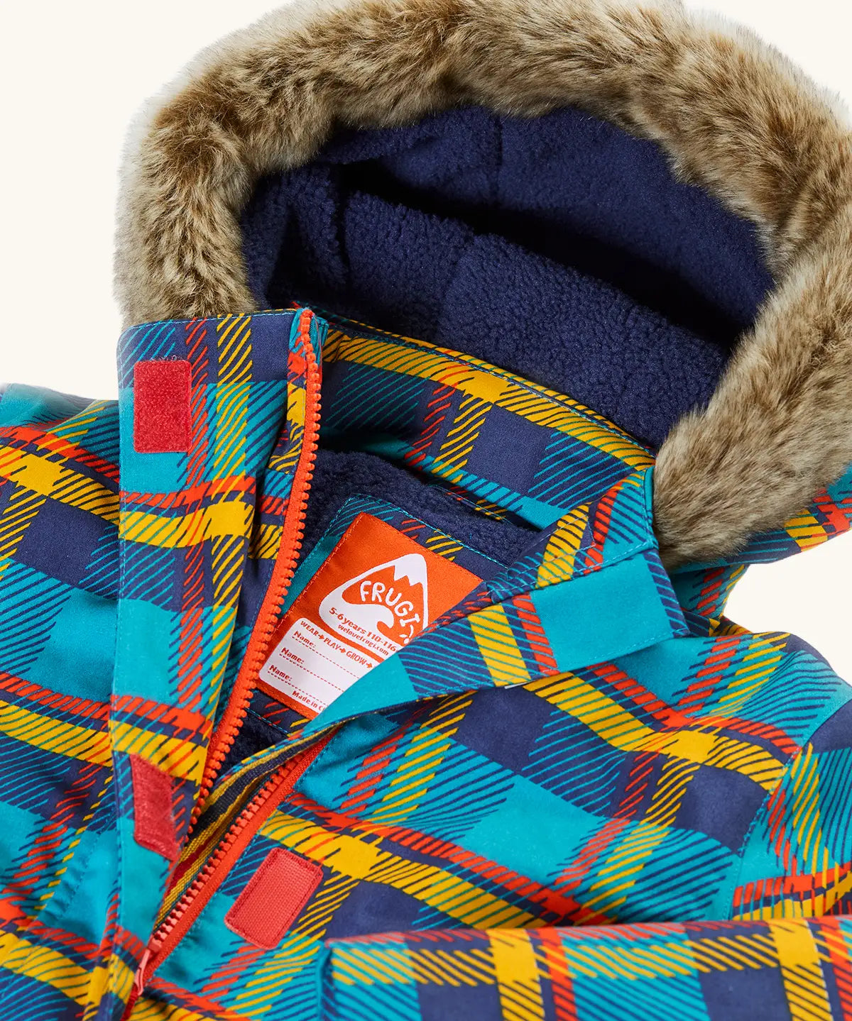 Frugi's Penhale parka coat in a blue red and yellow tartan check laid flat showing fur trim on the hood and navy fleece inner liner