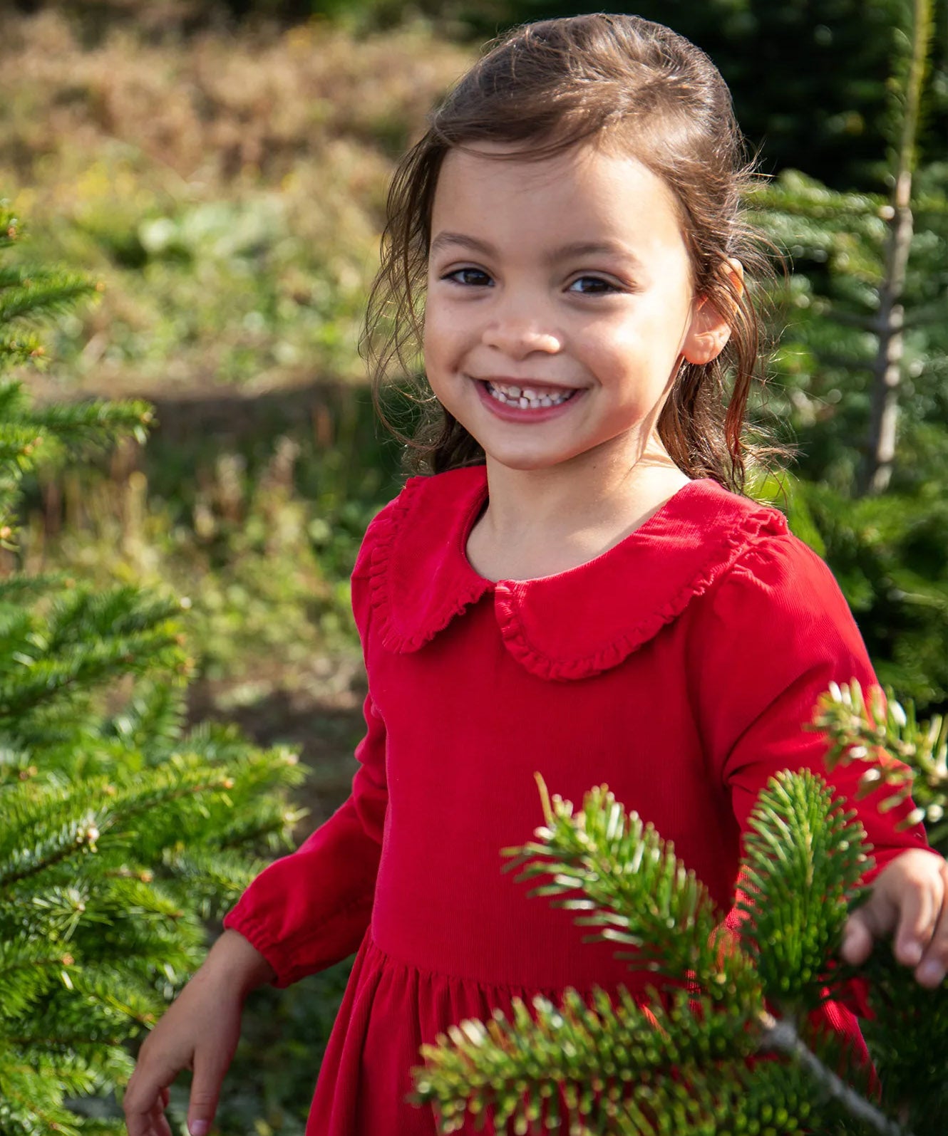 A close up of a child wearing Frugi Peony Corduroy Dress Red Robin showing the frilled collar detail. This is a Christmas party dress made from GOTS organic cotton - available at Babipur.
