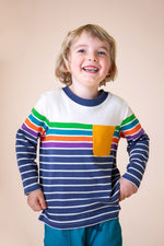 A child wearing the Frugi Piran pocket top in navy stripe available at Babipur. A GOTS organic cotton long sleeved top in a striped design. Features a yellow chest pocket