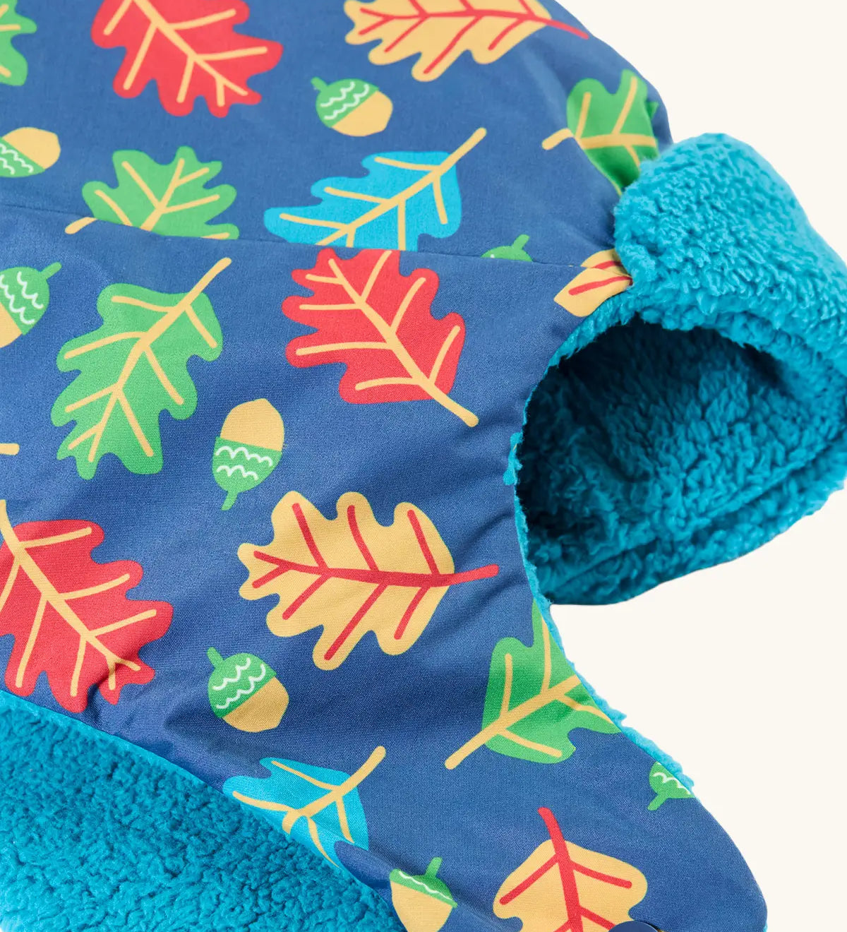 Frugi kids navy playtime trapper hat laid flat showing the repeating leaf and acorn design and aqua fleece inner lining.