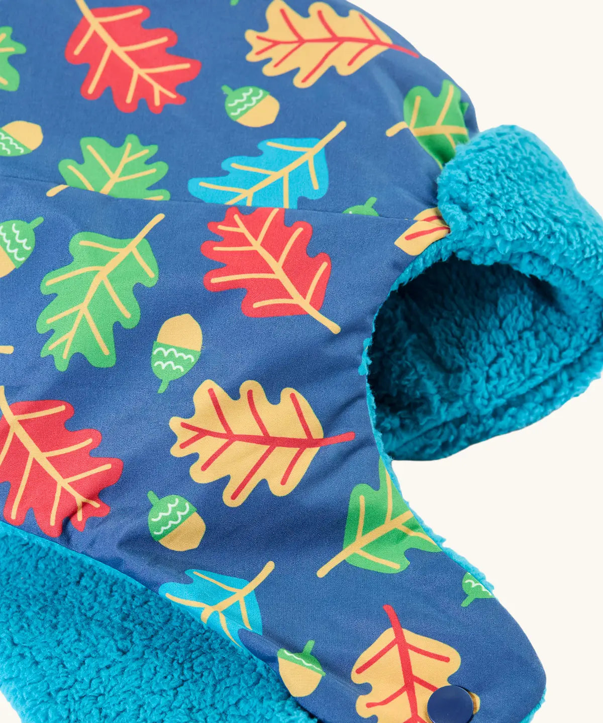 Frugi kids navy playtime trapper hat laid flat showing the repeating leaf and acorn design and aqua fleece inner lining.