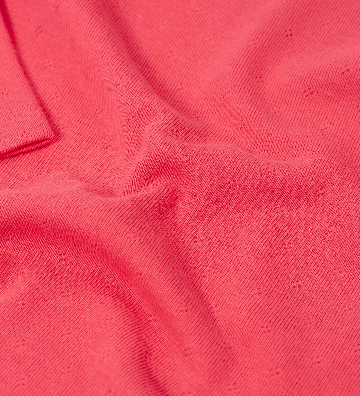 Frugi baby GOTS organic cotton pointelle body laid flat showing diamond stitch detail for breathability on pink organic cotton fabric 