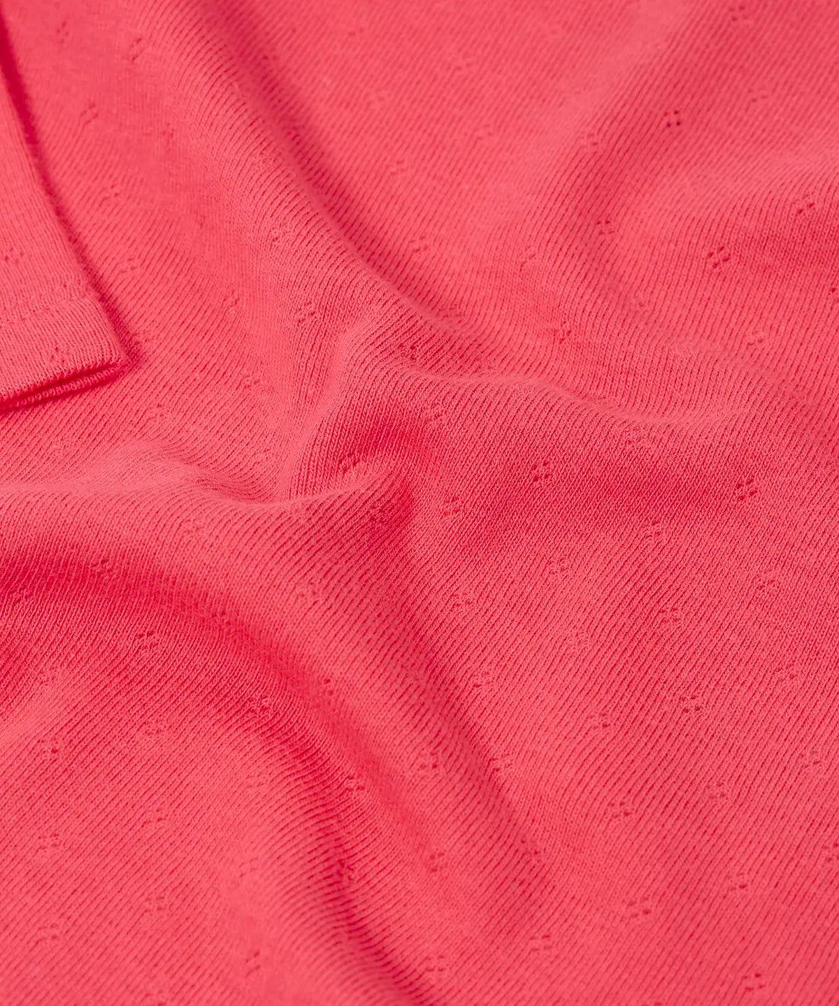 Frugi baby GOTS organic cotton pointelle body laid flat showing diamond stitch detail for breathability on pink organic cotton fabric 