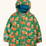 Frugi waterproof puddle buster coat in highland grazing. A green hooded coat with a repeating Highland cow design, side pockets and a blue fleece inner