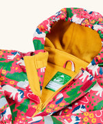Frugi waterproof puddle buster coat in purrfect ponies laid flat showing the zip and velcro fastener and yellow fleece inner liner with name tag