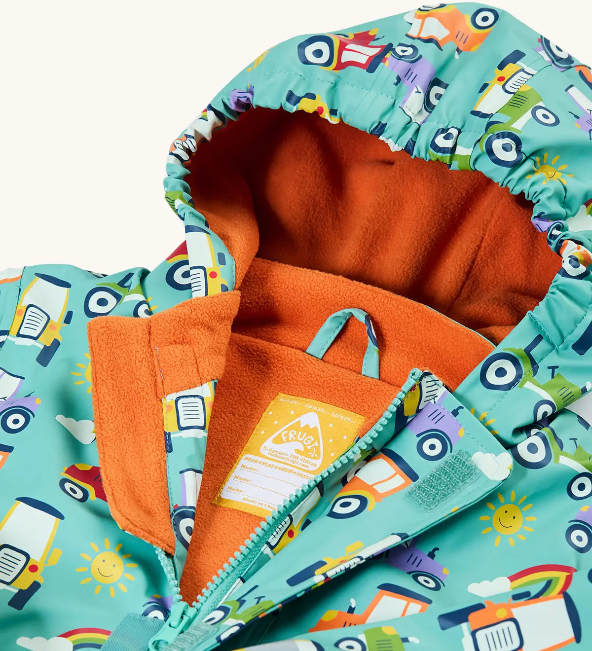 Frugi waterproof puddle buster coat in terrific tractors laid flat showing the front zip with velcro fastener and orange fleece liner with name tag