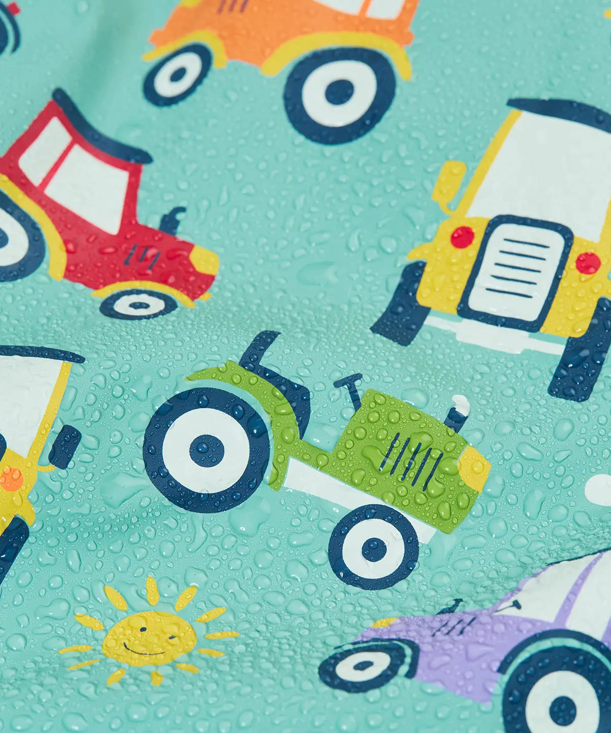 Frugi waterproof puddle buster coat in terrific tractors showing a close up of the repeating tractor design and water beading