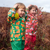 Children wearing Frugi's puddle buster waterproof coats one in green highland grazing design and the other in pink purrfect ponies