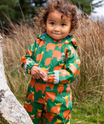 Small child wearing the Frugi waterproof green highland cow puddle buster all in one with the hood down