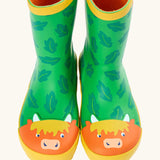 Front of Frugi puddle buster wellington boots showing the repeating leaf design and highland cow toe cap on green natural rubber material