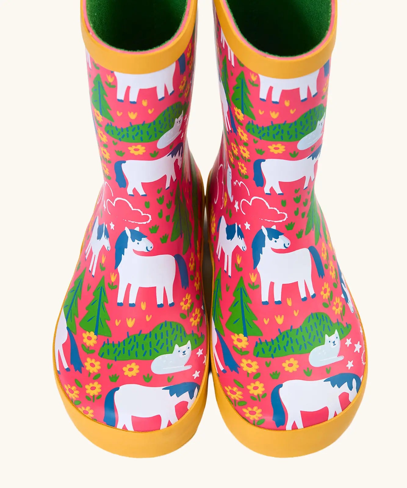Front of Frugi puddle buster wellington boots showing the repeating cat and pony design on pink natural rubber material