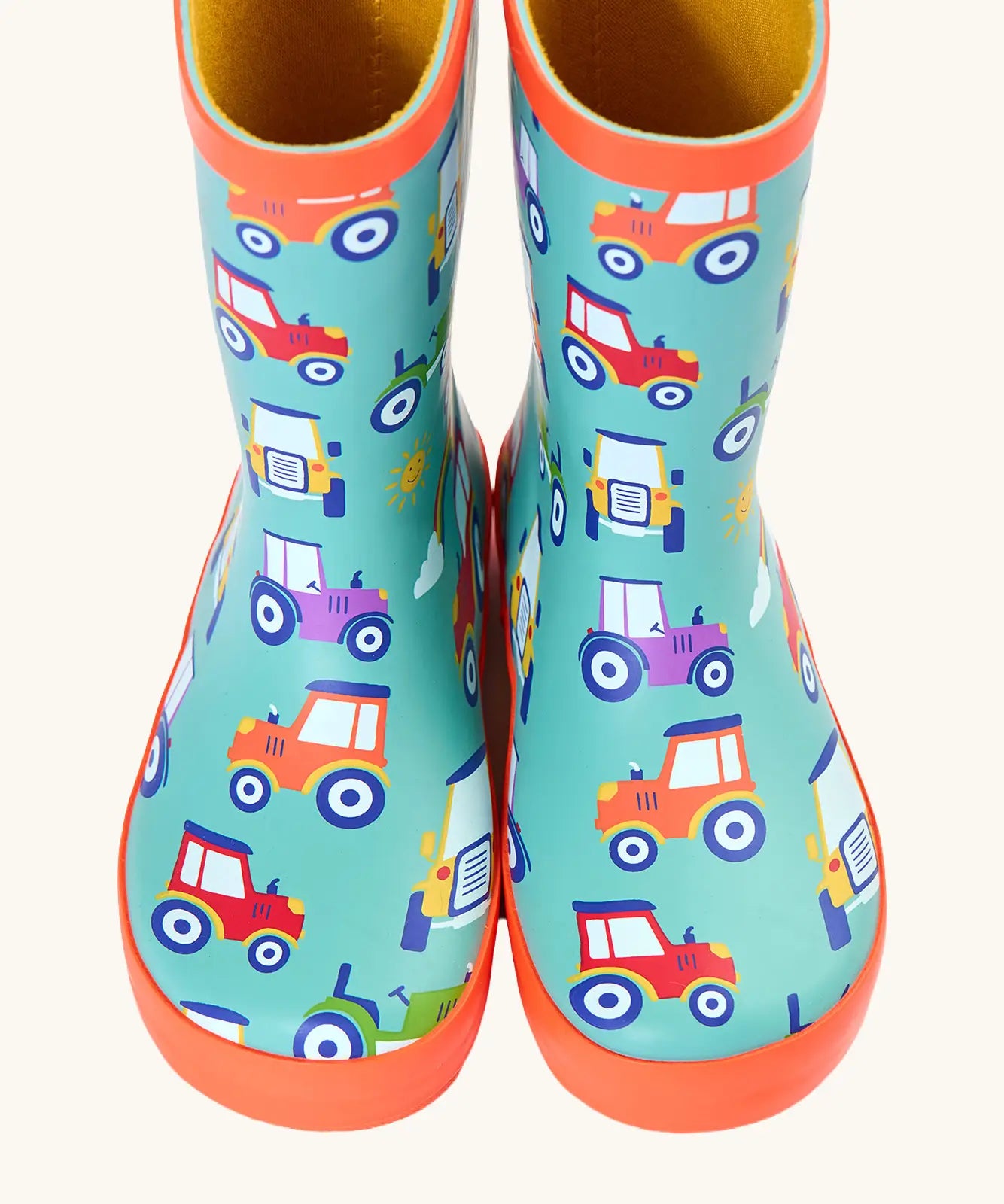 Front of Frugi puddle buster wellington boots showing the repeating tractor design on aqua natural rubber material