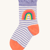 The lilac and white stripe sock from the Frugi Freya Frilled Socks 3 Pack - Rainforest Friends This sock has an orange toe and heel, and a rainbow on the side. It also has a solid purple ankle frilly cuff