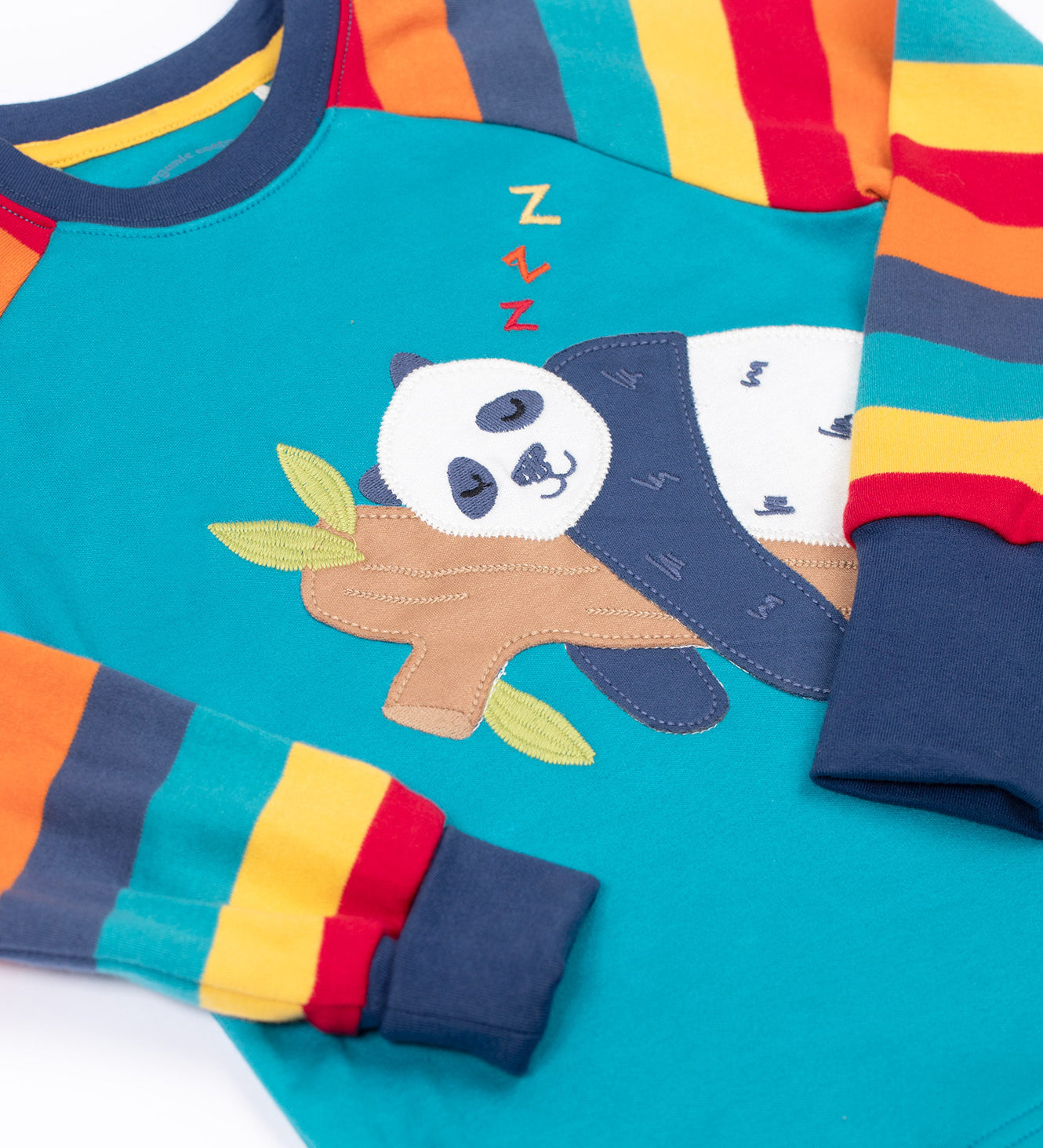 A close up of the sleeping panda applique on the Frugi rainbow  stripe / panda Jamie jim jam top available at Babipur. 