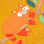 A closer look at the Red Panda on a tree branch applique. The Panda has a smiling face, an orange body and tail, with red ear tips, red tail stripes and red paws. The branch is light brown and the leaves are light and dark green.