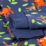 A closer look at the blue, elasticated rubbed cuffs on the Frugi Snuggle Suit - Red Panda Pals. The image also shows the red pandas, leaves and branch patterns, along with part of the snuggle suit zip