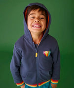 Frugi reversible navy zipped hoodie with elasticated rainbow cuffs with orange fleece lining, worn by boy.