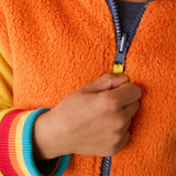 Frugi reversible organic cotton hoodie in orange recycled fluffy fleece with rainbow elasticated cuffs, worn by child.