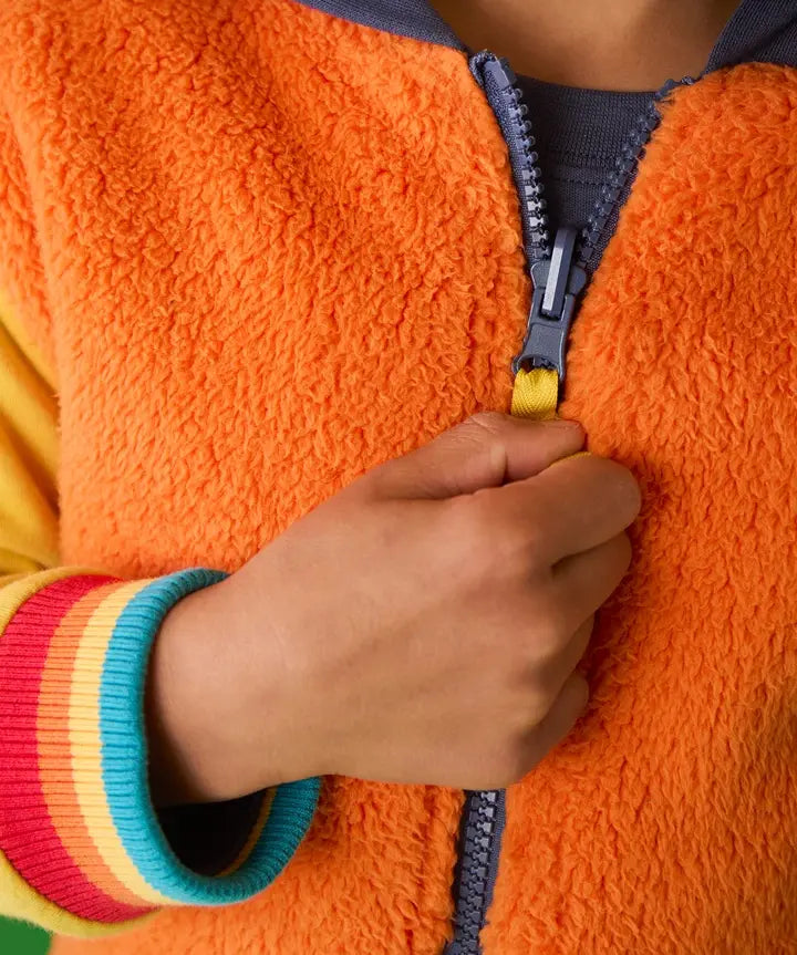 Frugi reversible organic cotton hoodie in orange recycled fluffy fleece with rainbow elasticated cuffs, worn by child.