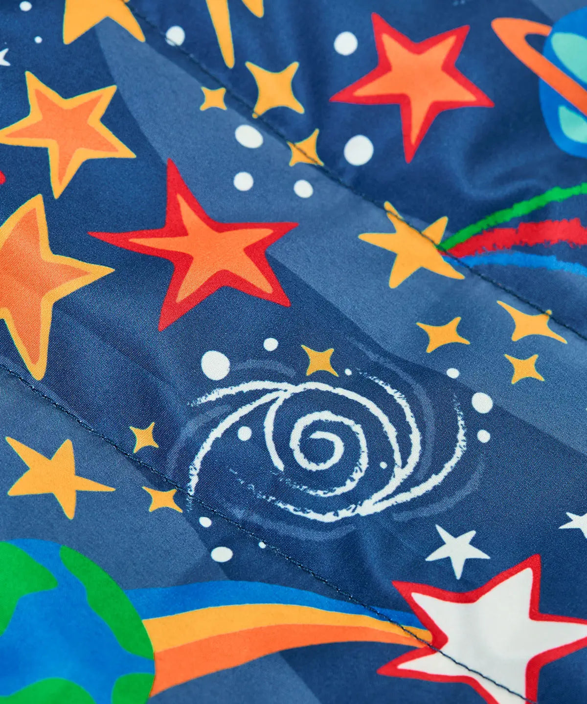 Frugi reversible toasty trail jacket in explore the stars showing a close up of the repeating outer space design on navy post consumer polyester material