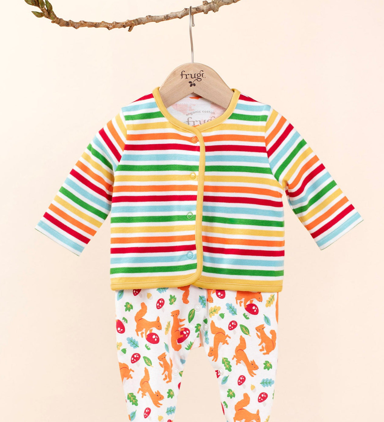 Frugi scrumptios babygrow set in squirrel friends hanging on a branch and  available at Babipur. A 100% GOTS organic cotton set including a white babygrow with playful squirrel prints and a rainbow striped cardigan. 