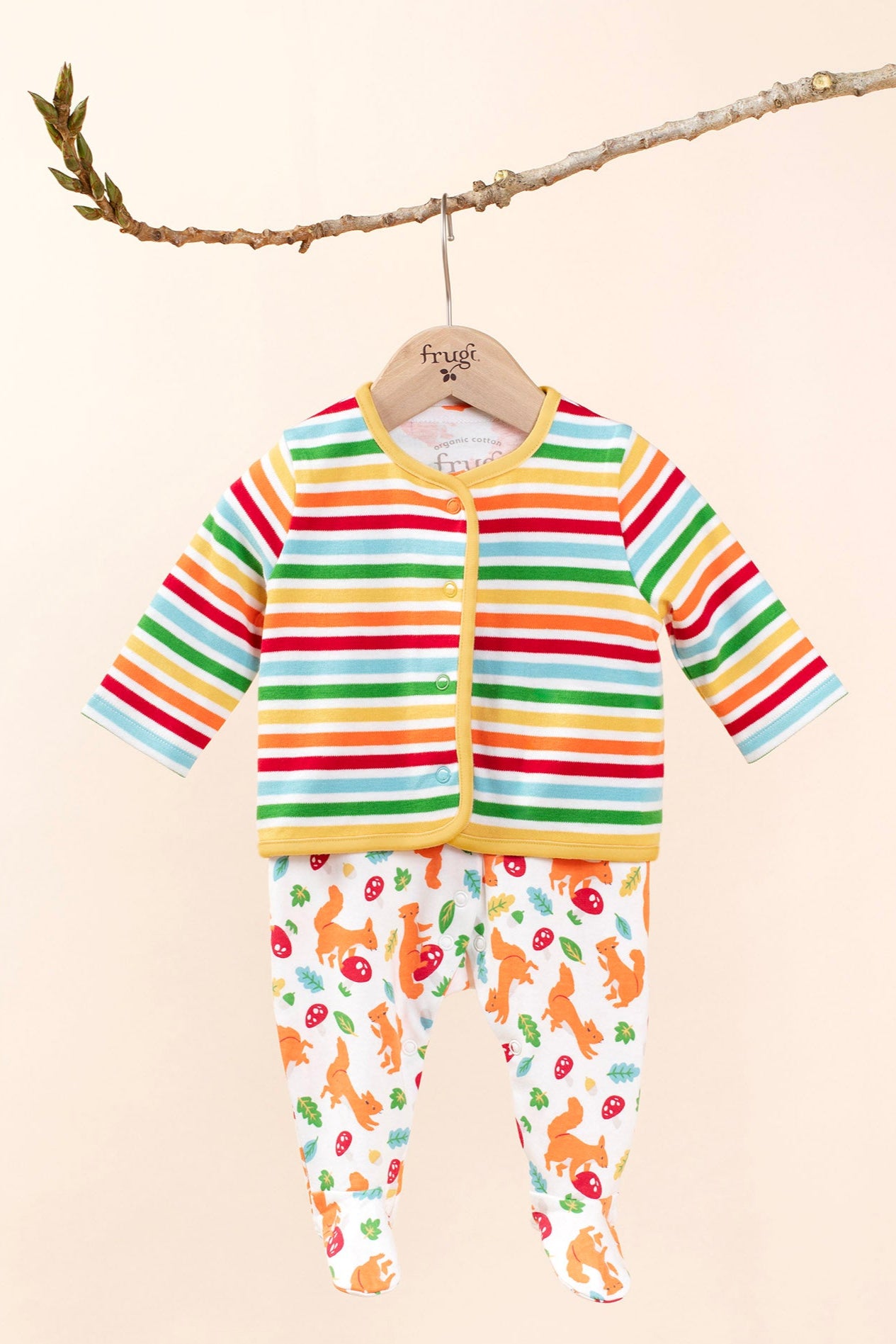 Frugi scrumptios babygrow set in squirrel friends hanging on a branch and  available at Babipur. A 100% GOTS organic cotton set including a white babygrow with playful squirrel prints and a rainbow striped cardigan. 