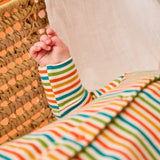 Frugi scrumptious baby with striped orange babygrow, made from organic cotton.