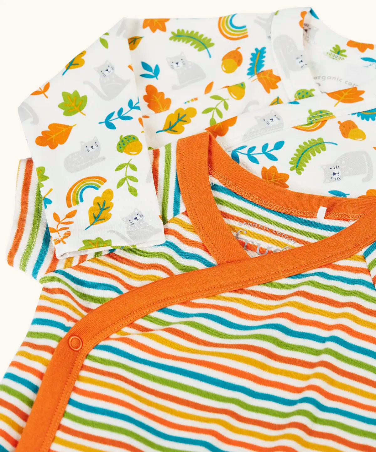 Frugi GOTS organic cotton baby bodysuit with multicoloured stripes and orange trim, laid on a white bodysuit with a repeating cat and leaf print.