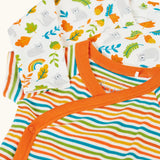 Frugi GOTS organic cotton baby bodysuit with multicoloured stripes and orange trim, laid on a white bodysuit with a repeating cat and leaf print.