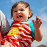Baby wearing Frugi's towelling romper with blue sleeves, white and red stripe body and yellow sun patch 