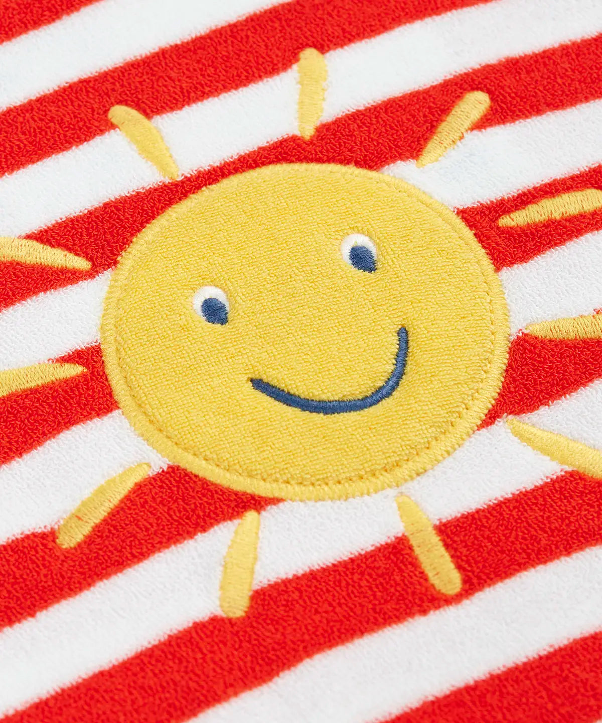 Frugi baby towelling romper laid flat showing white and red stripe body, yellow sun patch