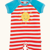 Frugi baby towelling romper with blue sleeves, white and red stripe body, yellow sun on the front and popper fasteners