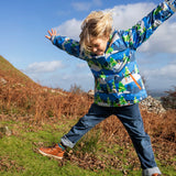 Child jumping in a field and wearing the Frugi recycled polyester snow and ski coat in starry slopes 
