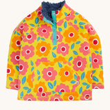 Frugi organic cotton fleece laid flat. In yellow with a navy fleece inner and a repeating floral print with a 1/4 length popper fastener