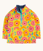 Frugi organic cotton fleece laid flat. In yellow with a navy fleece inner and a repeating floral print with a 1/4 length popper fastener