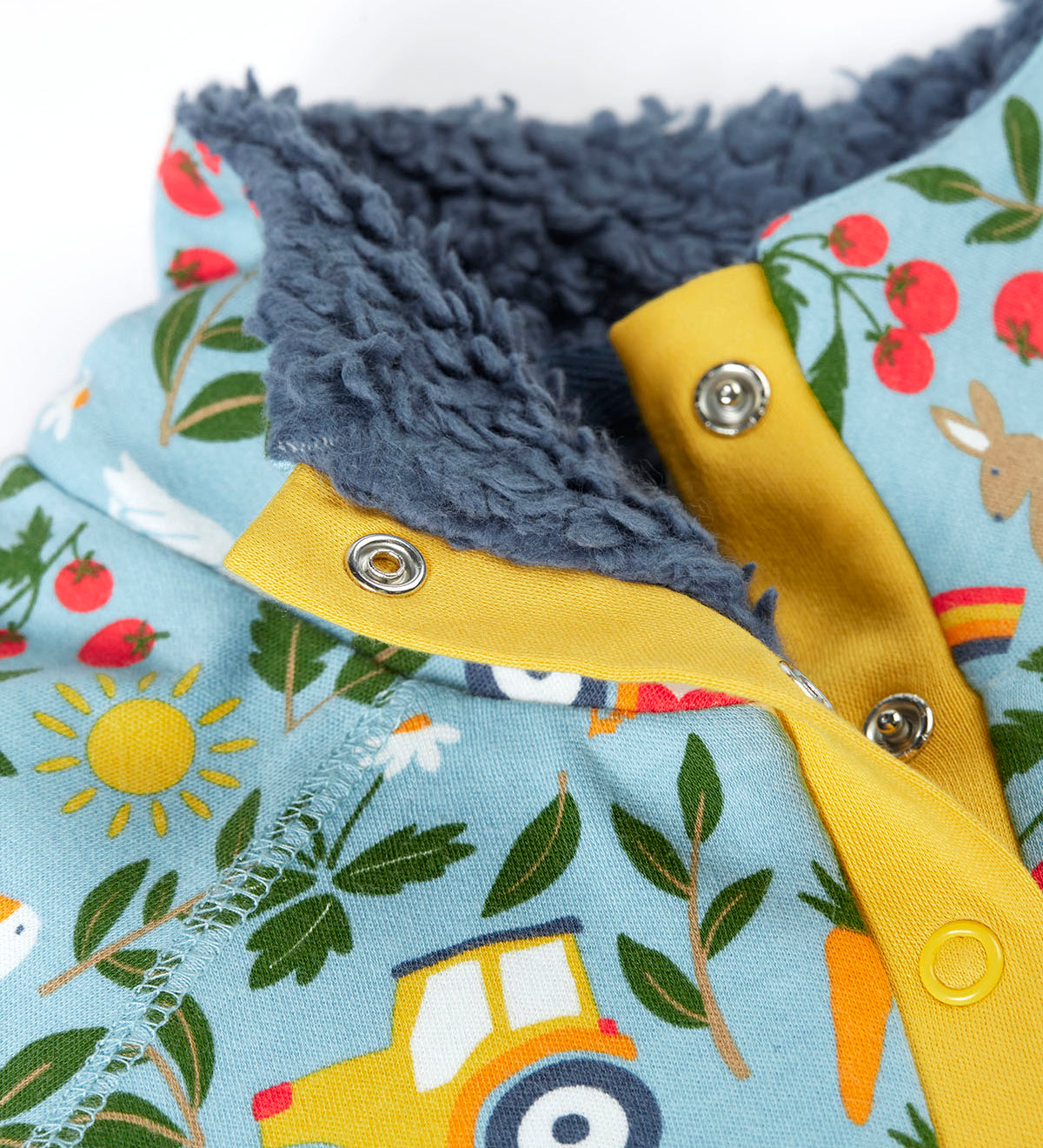 Close up of the light blue Frugi fleece showing the dark blue fleece inner and repeating farm themed print