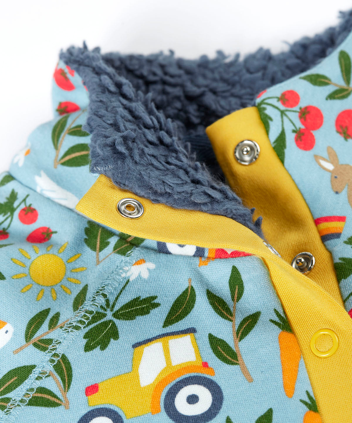 Close up of the light blue Frugi fleece showing the dark blue fleece inner and repeating farm themed print