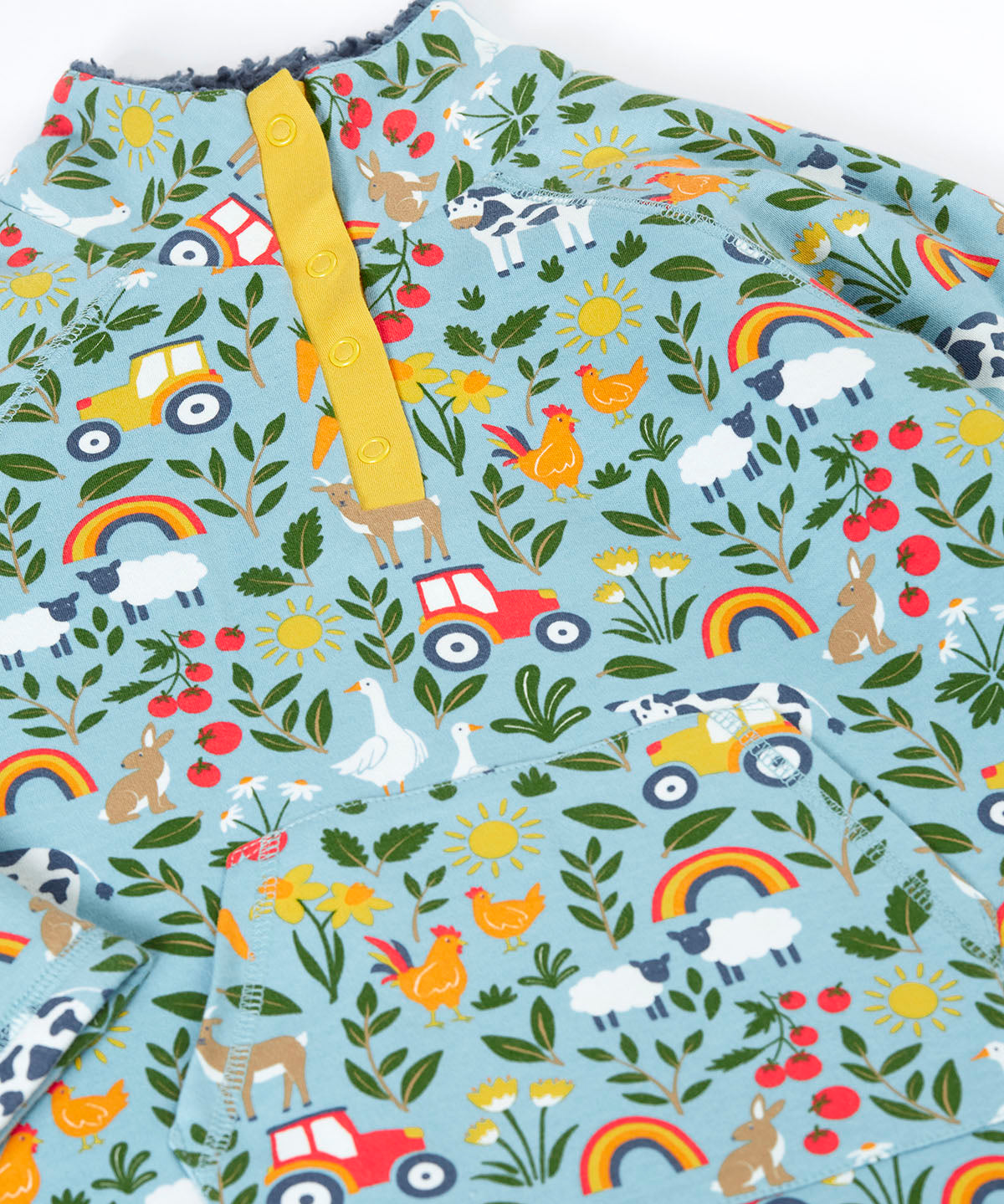 A close up of the light blue Frugi organic cotton fleece laid flat showing the repeating farm themed print and pouch pocket.