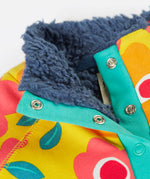 A close up of the yellow Frugi organic cotton fleece laid flat showing the navy fleece inner and 2 popper fasteners opened