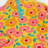 A close up of the yellow Frugi organic cotton fleece laid flat showing the repeating floral print and pouch pocket
