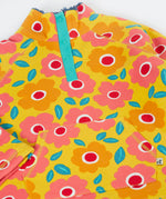 A close up of the yellow Frugi organic cotton fleece laid flat showing the repeating floral print and pouch pocket