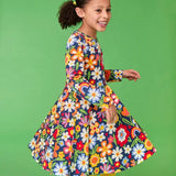 Frugi twirly sofia skater dress in navy beautiful bunch floral print, knee length with long sleeves, worn by girl.