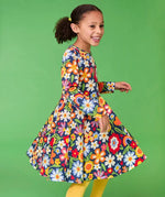 Frugi twirly sofia skater dress in navy beautiful bunch floral print, knee length with long sleeves, worn by girl.
