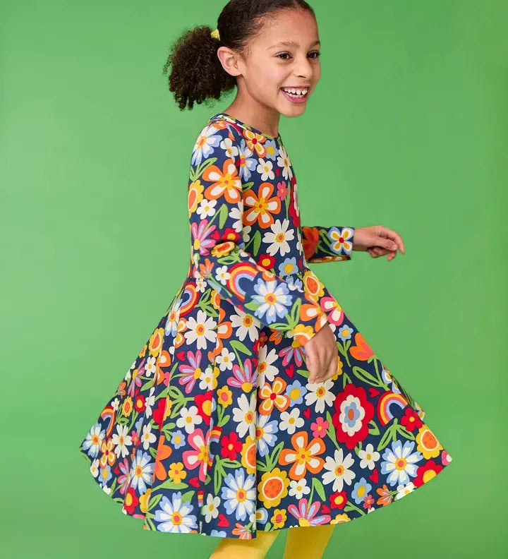 Frugi twirly sofia skater dress in navy beautiful bunch floral print, knee length with long sleeves, worn by girl.