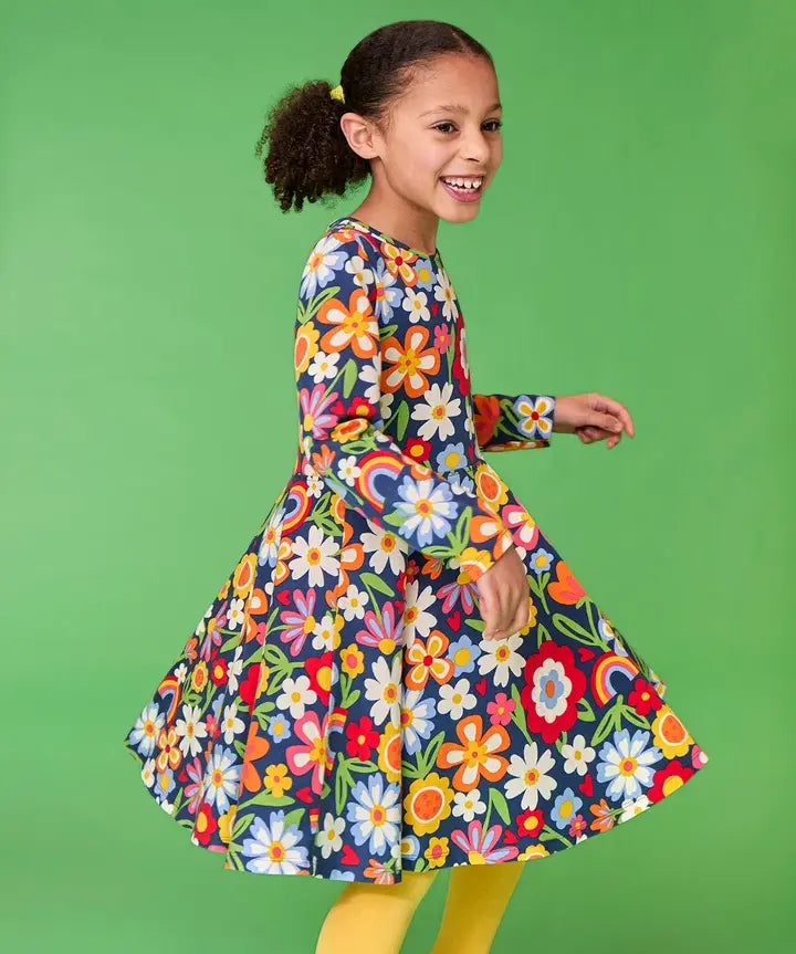Frugi twirly sofia skater dress in navy beautiful bunch floral print, knee length with long sleeves, worn by girl.