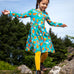 Frugi sofia skater dress in blue Highland cow print, knee length with long sleeves, worn by girl outside.