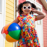 Child wearing Frugi's favourite things Spring skater dress and holding a rainbow beach ball
