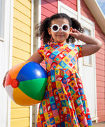 Child wearing Frugi's favourite things Spring skater dress and holding a rainbow beach ball